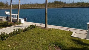 A boat docked by a calm lake with a grassy area and palm trees in the foreground. - Tallis Palace. 1-bedroom apartment with WiFi, AC in sunny Freeport. Car offered. (Freeport)