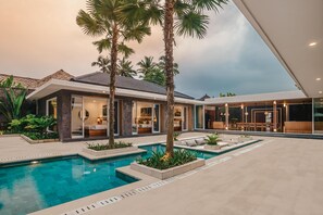 A modern house with a swimming pool, outdoor seating, and a large glass door leading to a patio. - Villa Dune (Ubud)
