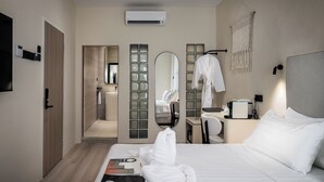 A modern hotel room with a large bed, a bedside table with a lamp, a mirror, and a wall-mounted air conditioner. - Muntri Maison (George Town)