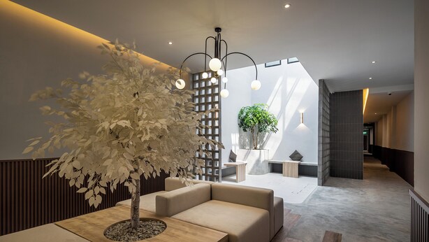 A modern lobby with a central seating area, a decorative tree, and a staircase leading to upper floors. - Muntri Maison (George Town)