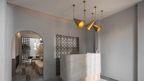 A reception area with a modern design, featuring a reception desk, a patterned wall, and a staircase leading to another room. - Muntri Maison (George Town)