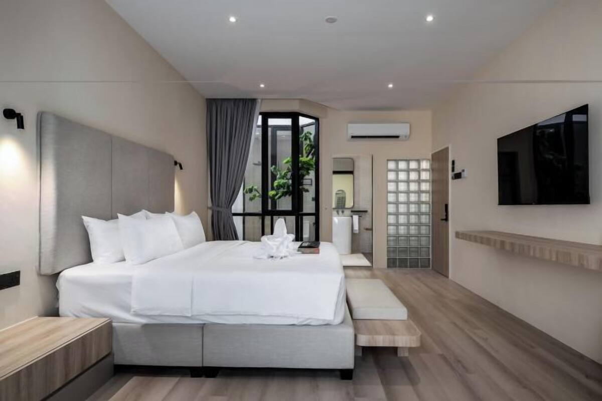 Une chambre d’hôtel moderne, dotée d’un grand lit, d’une télévision et offrant une vue sur l’extérieur.
