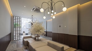 A modern lobby with a seating area, a decorative tree, and a unique lighting fixture. - Muntri Maison (George Town)