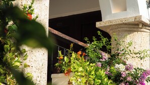 Una columna de piedra con un arco blanco, rodeada de exuberante follaje y flores coloridas.