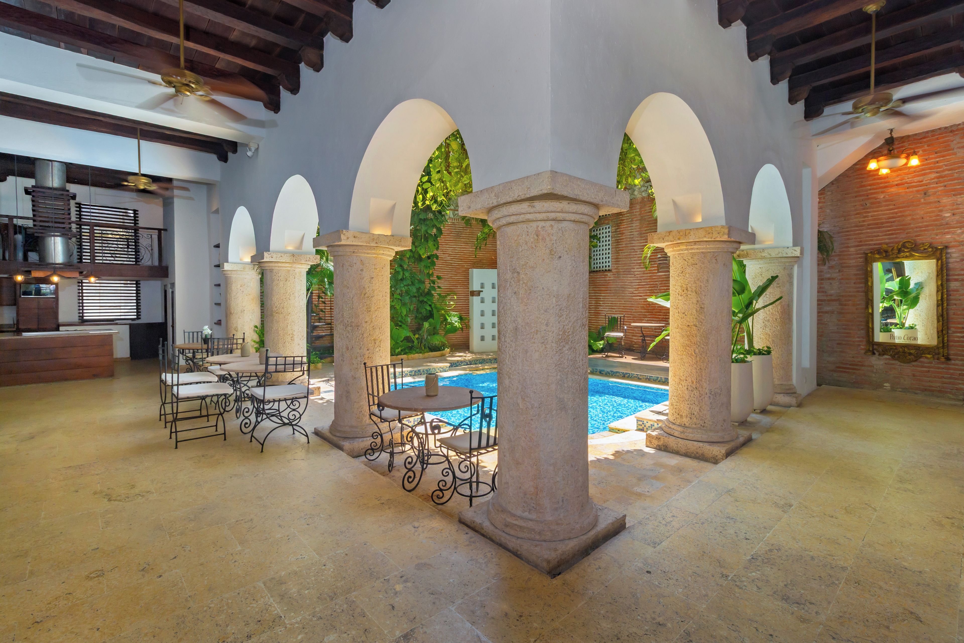 A spacious indoor area with a pool, stone columns, and a bar area.