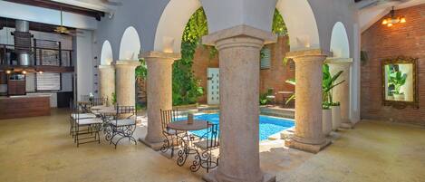 A spacious indoor area with a pool, stone columns, and a bar area.