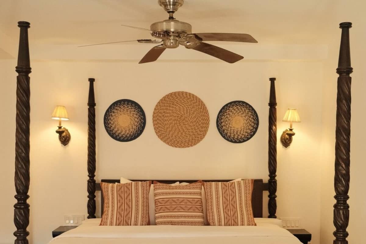 A four-poster bed with a ceiling fan, wall sconces, and decorative plates.
