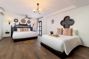 Habitación de hotel con dos camas, ventilador de techo, lámparas de pared y espacio para café.