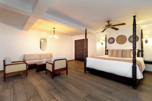 A hotel room with a four-poster bed, a sofa, two armchairs, a ceiling fan, and wall-mounted lamps. - Hotel Boutique Patio Corao By GEH Suites (Cartagena)