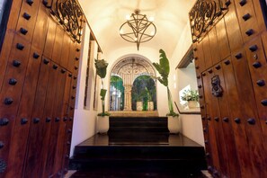 A wooden staircase leading to a room with a decorative ceiling light and a view of greenery outside. - Hotel Boutique Patio Corao By GEH Suites (Cartagena)