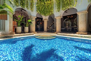 A swimming pool with tiled edges, surrounded by columns and arches, with hanging plants above. - Hotel Boutique Patio Corao By GEH Suites (Cartagena)
