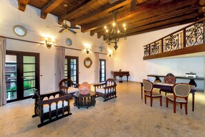 A spacious room with a high ceiling, wooden beams, a chandelier, and a piano. - Hotel Boutique Patio Corao By GEH Suites (Cartagena)