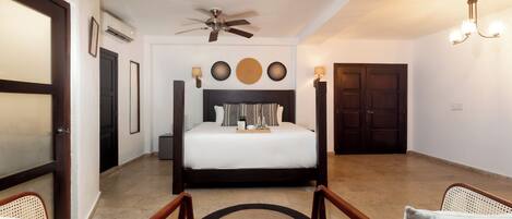 A bedroom with a bed, a ceiling fan, a wall-mounted lamp, and a door.
