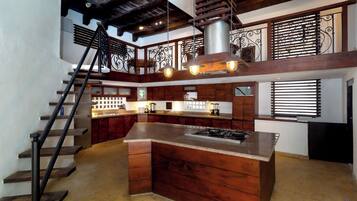 A kitchen with a central island, wooden cabinets, and a staircase.