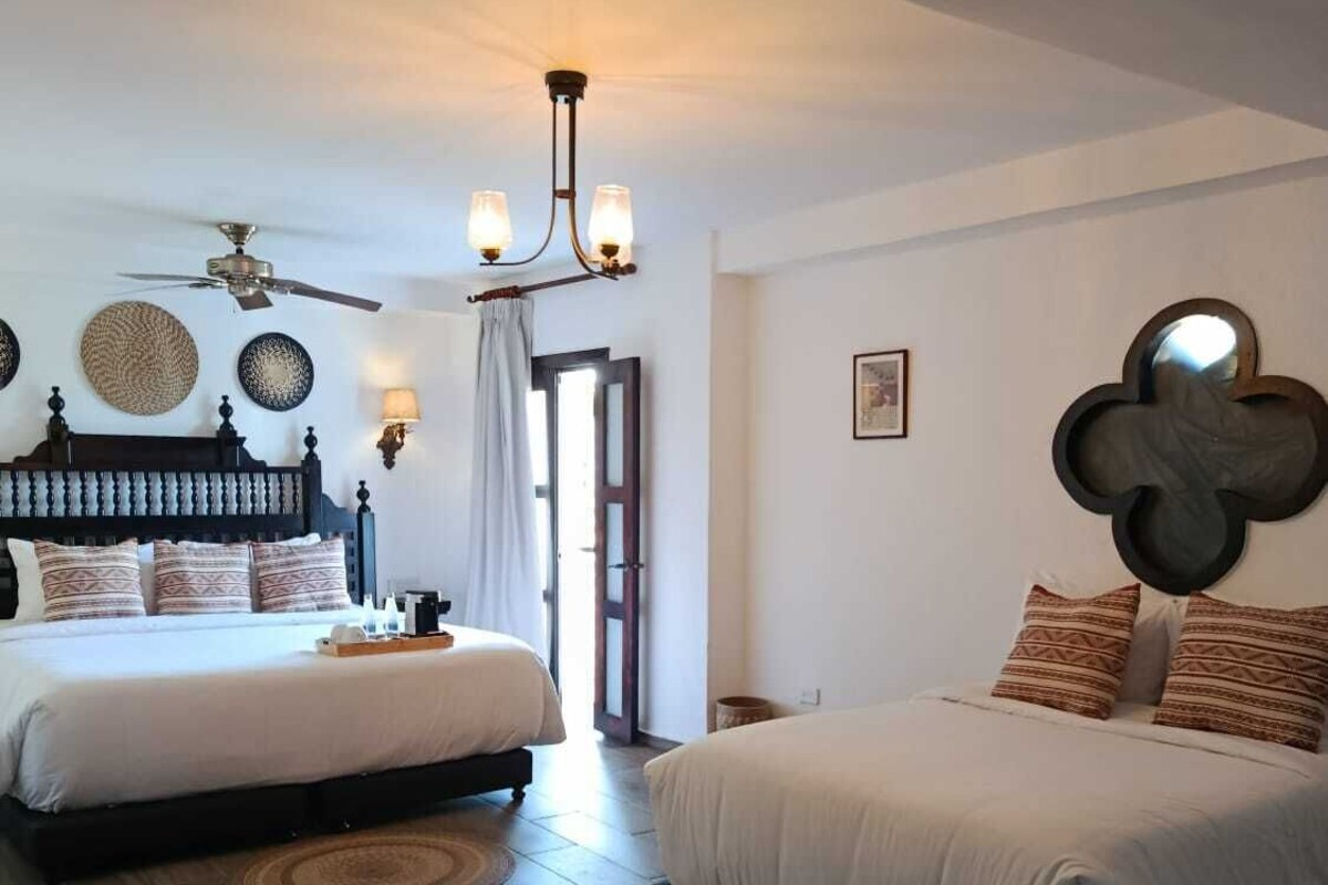 Quarto com duas camas, um ventilador de teto e um lustre.