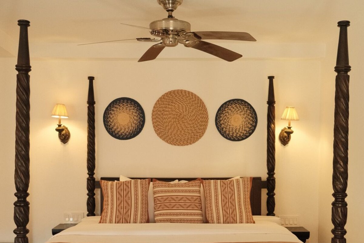 A four-poster bed with a ceiling fan, wall sconces, and decorative plates.