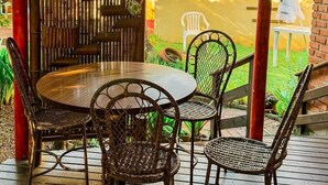 An outdoor patio with a round table and four wicker chairs. - Pousada To na Praia Campeche (Florianopolis)