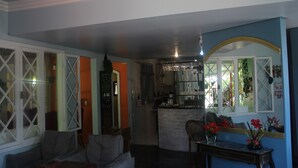 A living room with a sofa, a coffee table, and a dining area with a bar. - Pousada To na Praia Campeche (Florianopolis)