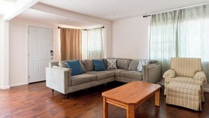 En stue med en hjørnesofa, et træsofa bord og en stribet lænestol.