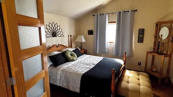 Une chambre à coucher avec un lit, un banc en bois, une table de chevet, une lampe et un miroir.