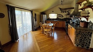 Una cocina amplia con armarios de madera, encimera de piedra y comedor con mesa y sillas.