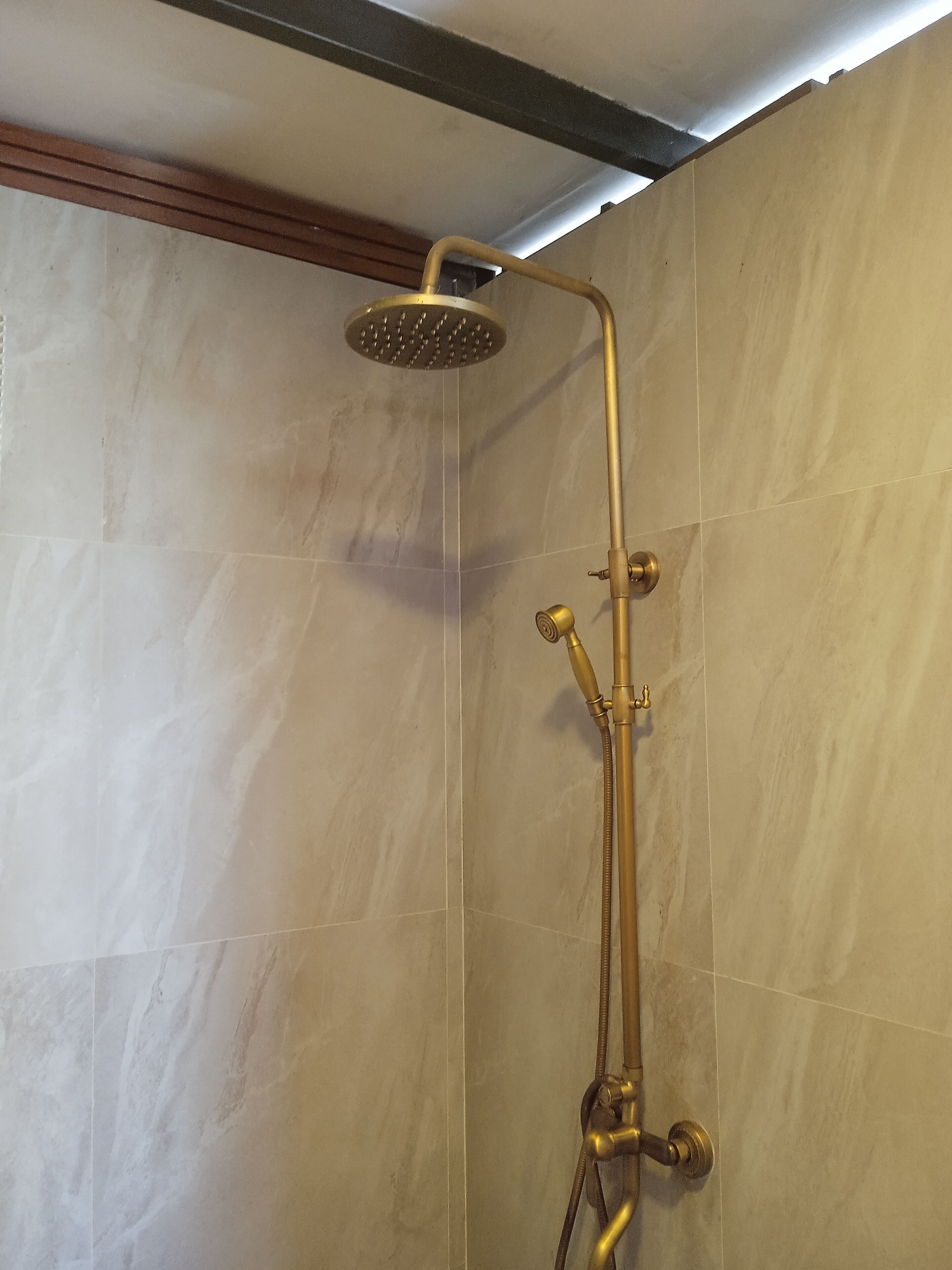A shower with a handheld showerhead and a wall-mounted control valve.