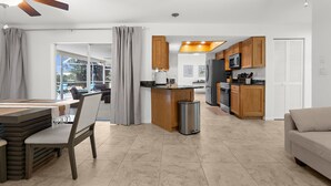 A modern kitchen with wooden cabinets, a built-in microwave, and a stainless steel refrigerator. - Charming Paradise w/ Beautiful Pool and waterfront Tiki Hut + Backyard Boat Ramp (Port Charlotte)