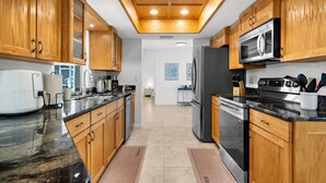 A kitchen with wooden cabinets, a stainless steel refrigerator, a microwave, and a coffee maker. - Charming Paradise w/ Beautiful Pool and waterfront Tiki Hut + Backyard Boat Ramp (Port Charlotte)