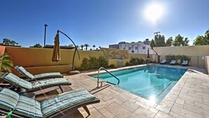 Un espace piscine aménagé sur le toit, avec des chaises longues et un parasol.