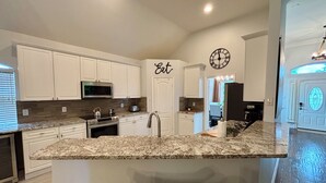 A modern kitchen with white cabinets, a granite countertop, and a clock on the wall. - New House/with Pool/Hot Tub/Putting Green/Close to Universal Studios/Theme Rooms (Frisco)