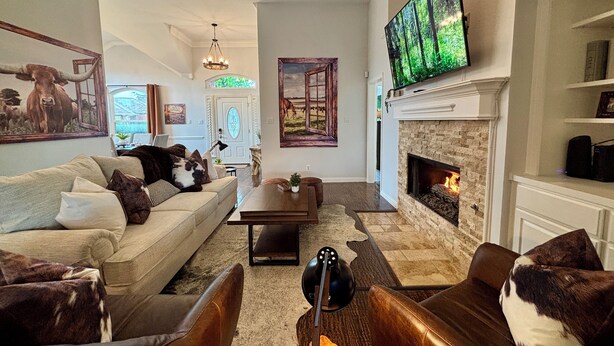 A living room with a fireplace, a television mounted above it, and a ceiling fan. - New House/with Pool/Hot Tub/Putting Green/Close to Universal Studios/Theme Rooms (Frisco)
