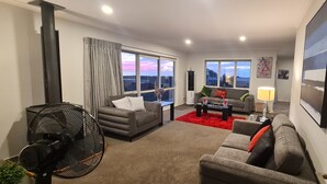 A living room with two sofas, a coffee table, a fan, and a large window with a view.