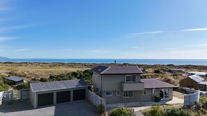Una casa de dos pisos con garaje, paneles solares y vista al océano.