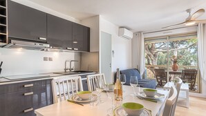 Eine moderne Küche mit dunklen Schränken, einem eingebauten Backofen und einem Essbereich mit Tisch für zwei Personen.