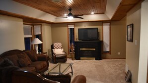Una sala de estar con chimenea, televisor y ventilador de techo.