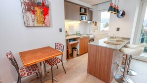 A modern kitchen with a wooden dining table, bar stools, and a small island.