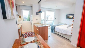 A compact hotel room with a kitchenette, a dining area, and a bed.