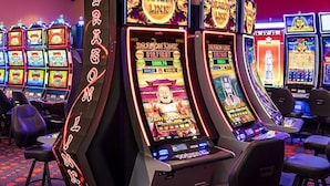 A row of slot machines with a neon sign reading "Dragon Link" in a casino setting.