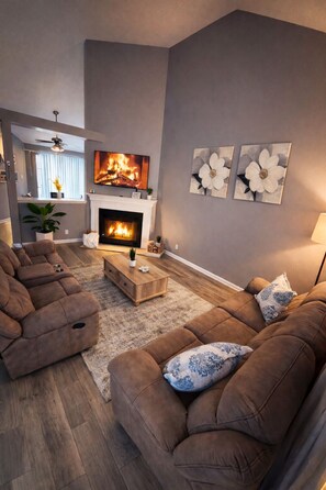 A living room with a fireplace, sofas, and artwork on the wall.