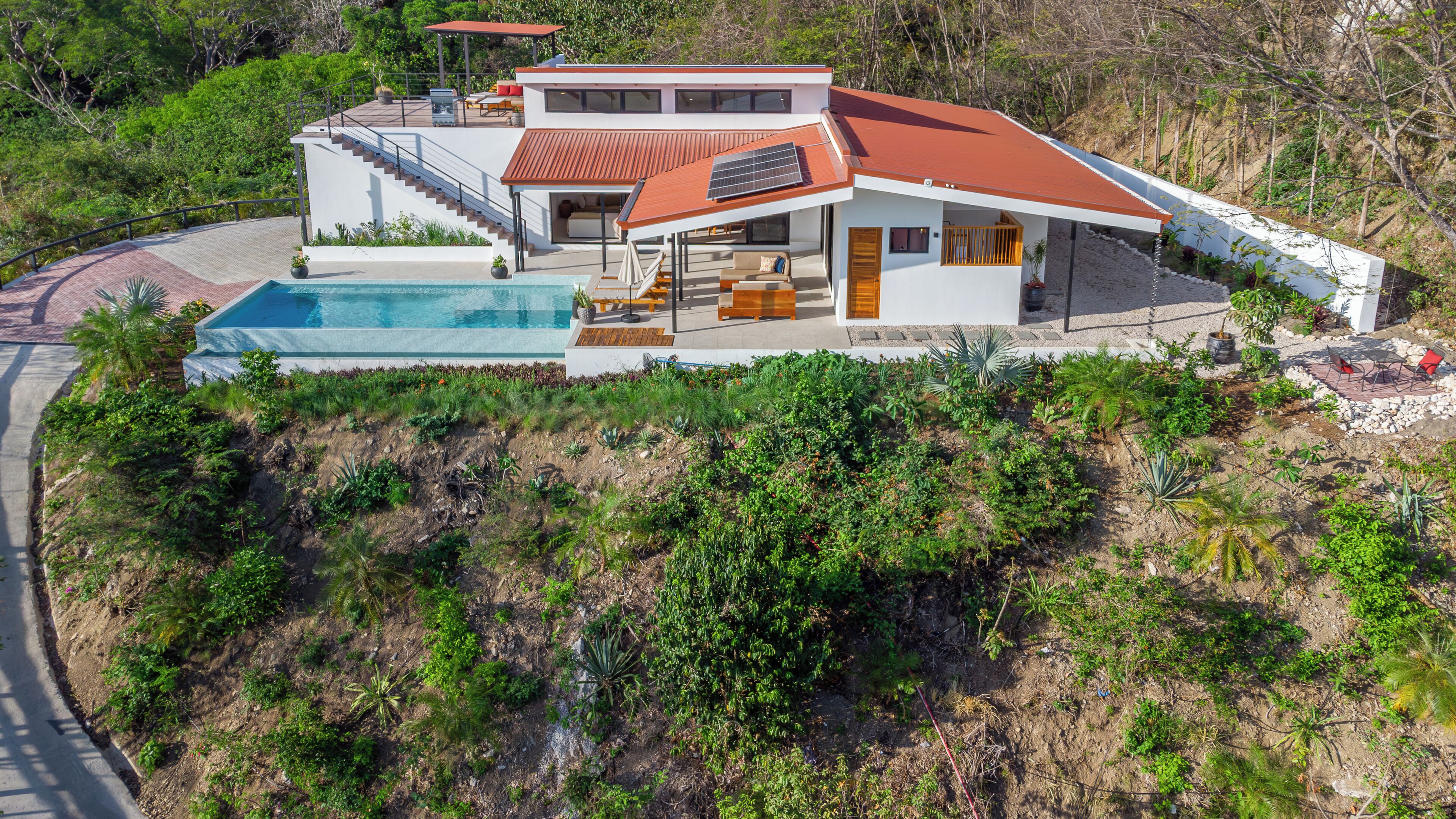 A modern house with a swimming pool, a covered patio, and a staircase leading to a second level.