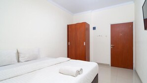 Une chambre à coucher avec un lit, deux armoires en bois et une porte.