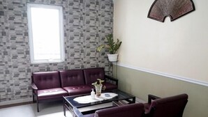 Une pièce avec un mur orné de motifs, une fenêtre, un canapé, une table et une plante en pot.