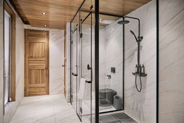 A modern bathroom with a glass-enclosed shower, marble walls, and a wooden door. - Jiuzhai Yunshang (Ngawa Autonomous Prefecture)