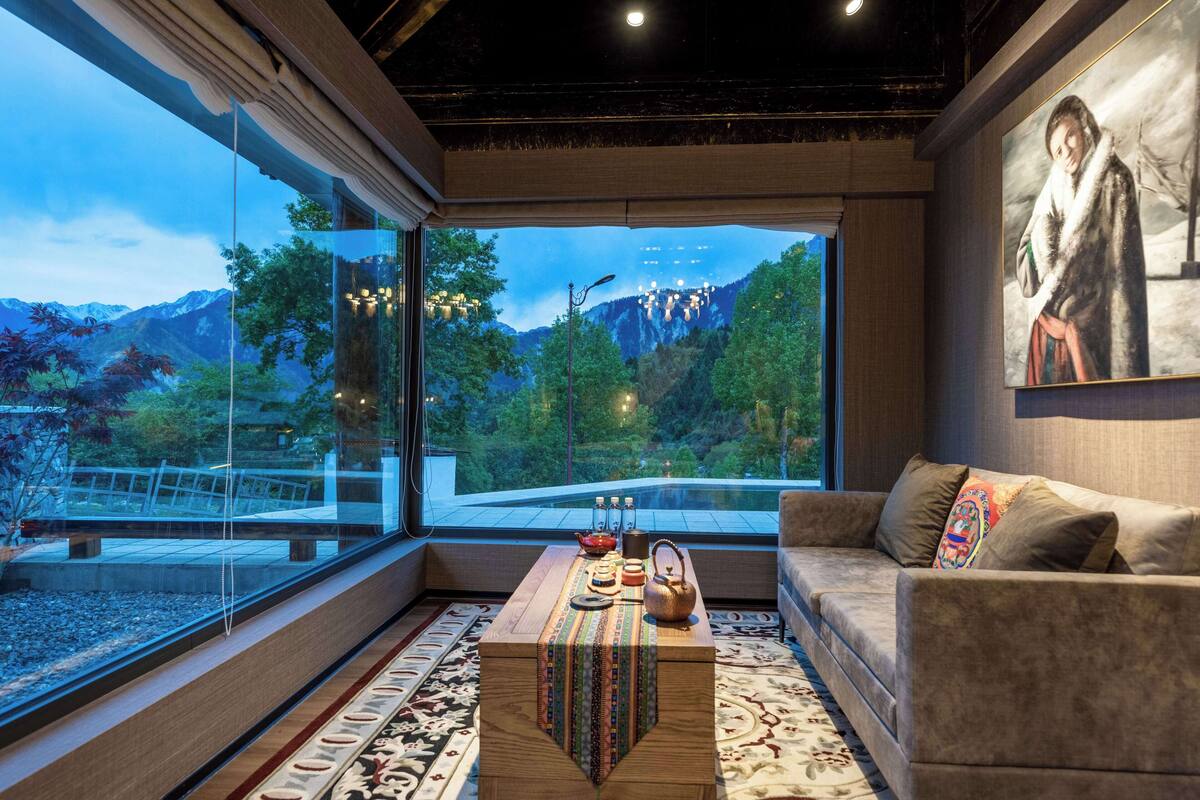 Ein modernes Wohnzimmer mit einem großen Fenster mit Blick auf eine gebirgige Landschaft.