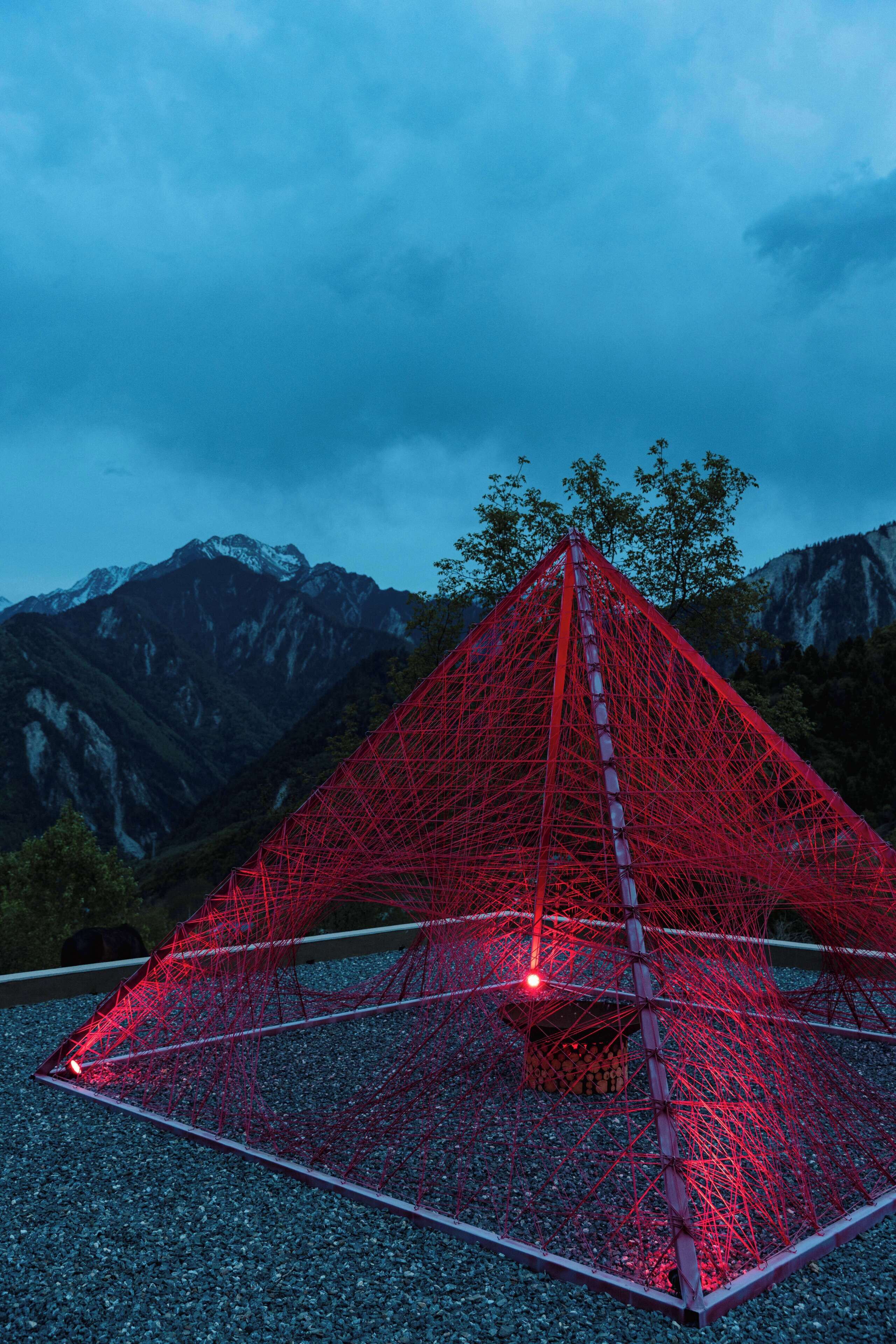 A red net structure with a ladder, set against a mountainous backdrop.