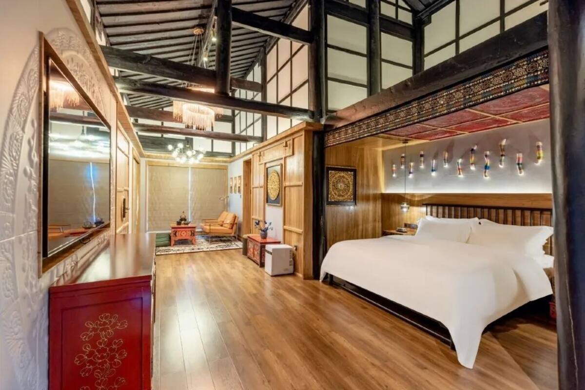 Ein geräumiges Hotelzimmer mit großem Bett, Holzboden, einer Kandelaber und einer traditionellen japanischen Wand mit hängenden Flaschen.