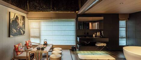 A modern interior with a tatami mat dining area, a large bathtub, and a minimalist bathroom.