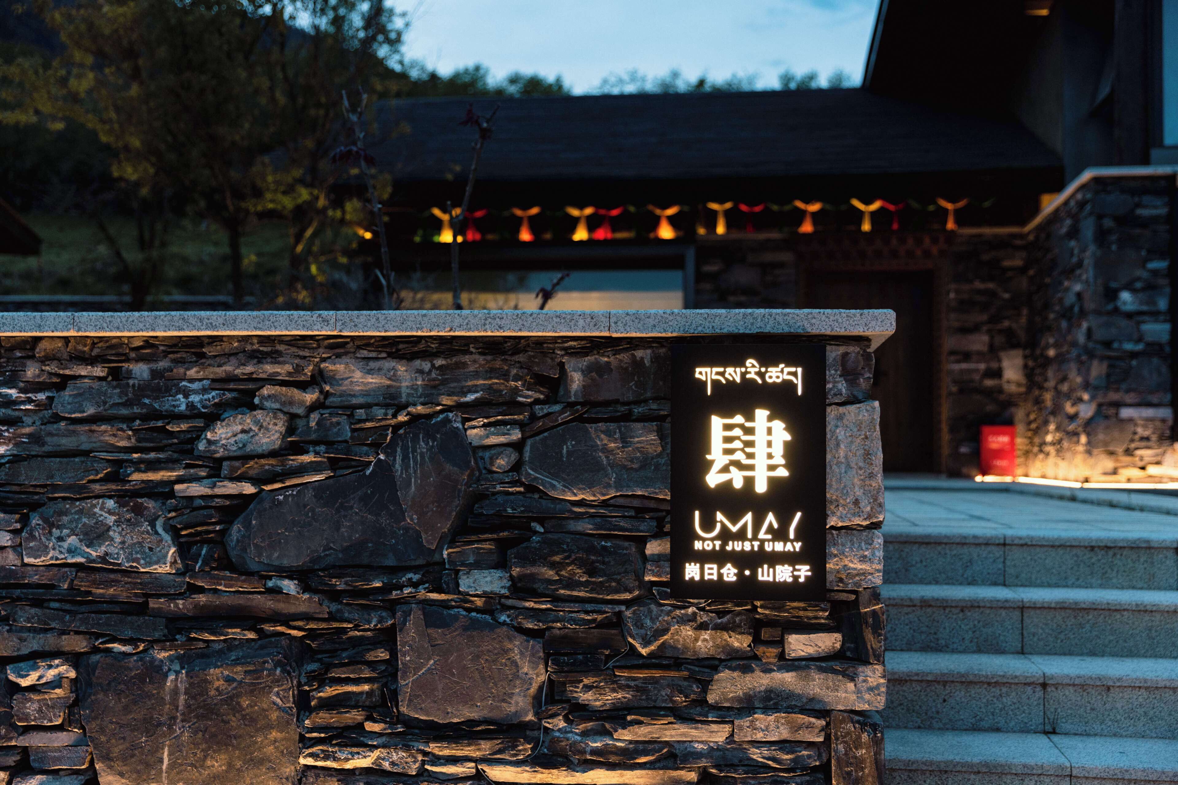 A stone wall with a sign in a foreign language and the text "UMAI NOT JUST UMAI".