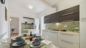 A modern kitchen with white cabinets, a tiled backsplash, and a dining area with a table set for four.