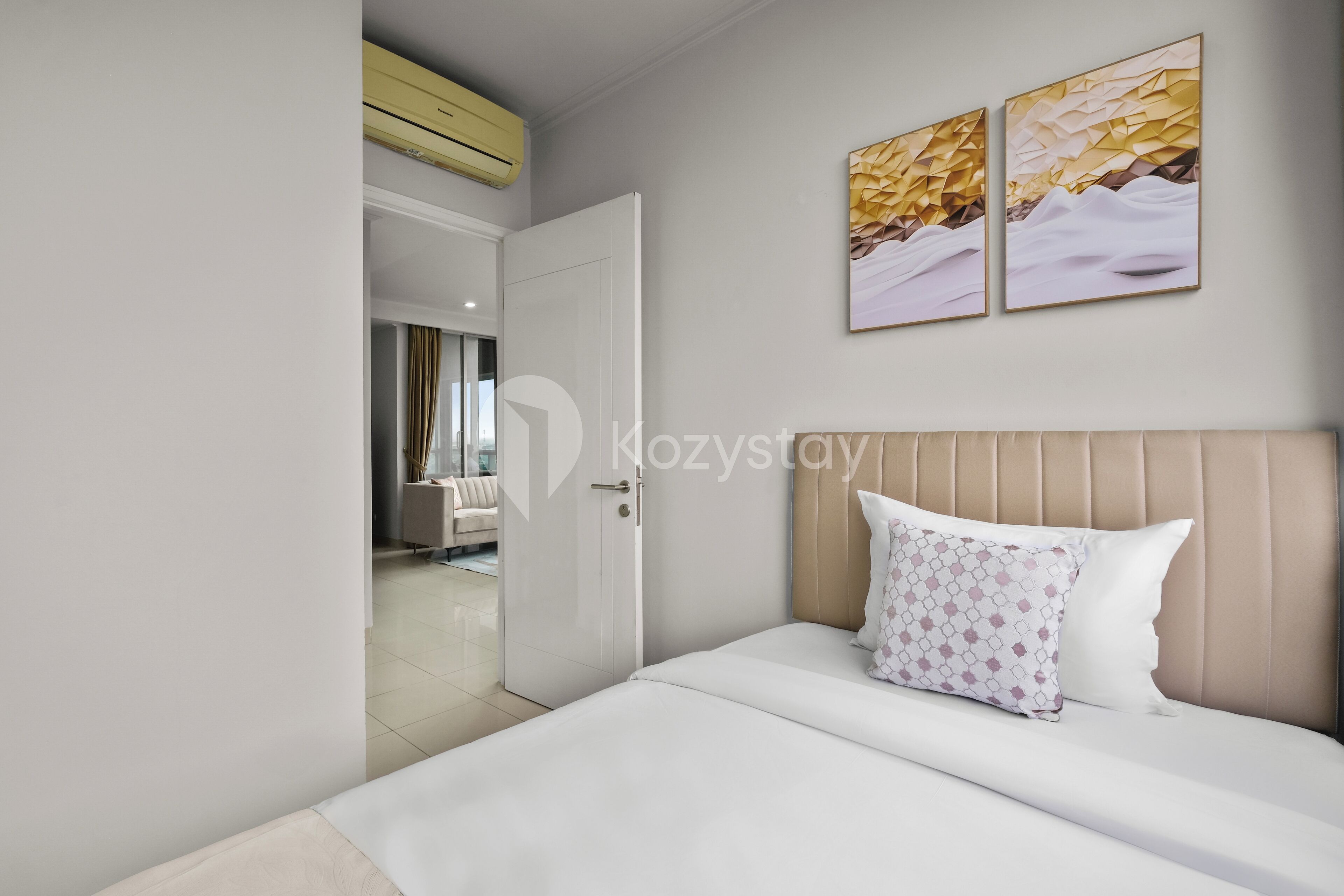A modern hotel room with a large bed, a headboard, and two wall-mounted artworks.